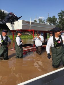 TF2 members in floodwater unloading a boat off of the top level of a boat trailer